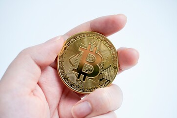 Hand holding gold bitcoin cryptocurrency isolated on white background.
