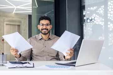 In a modern office, a professional man is seen intensely working at his desk. His organized workspace enhances productivity, helping him excel and meet goals effectively