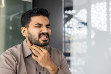 A man seems to be experiencing discomfort or pain in his throat, possibly indicating an illness....