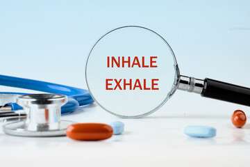 INHALE EXHALE written words through a magnifying glass on a light blue background, next to the pills