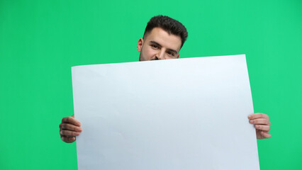 A man, close-up, on a green background, shows a white sheet