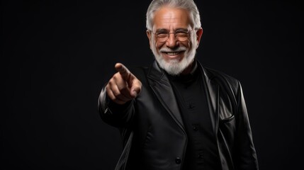 Fototapeta premium A mature professional man with a gray beard and glasses, dressed in a black jacket, gesturing to the side with a smile, symbolizing guidance, leadership, and assurance
