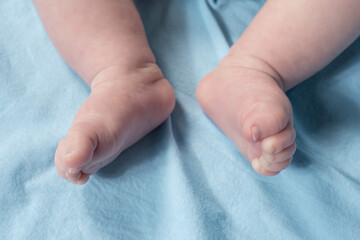 Close up view of newborn baby legs on a bed.