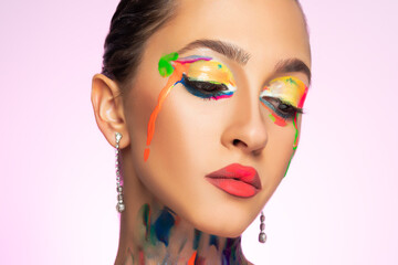 Fashion model with colorful paint on her face. Body Art design on bright background.