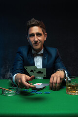 Happy poker player throwing a pair of aces at green table in casino.