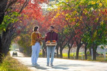 Happy caucasian farmer couple carrying organics homegrown produce harvest with apple, squash and...