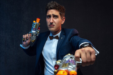 Funny businessman posing with toy guns against gray background.