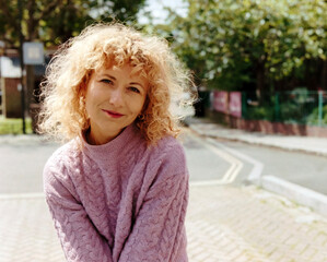 Analog portrait of smiling curly woman outdoors.