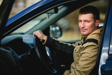 A man behind the wheel of a passenger car, navigating the road with confidence and focus.