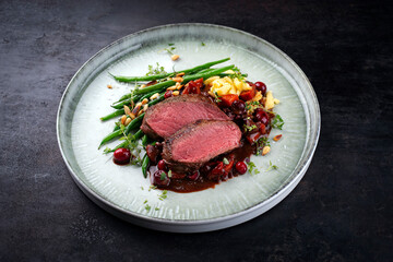 Traditionally roasted saddle of venison fillet with spätzle, vegetable and fruits in chocolate red...