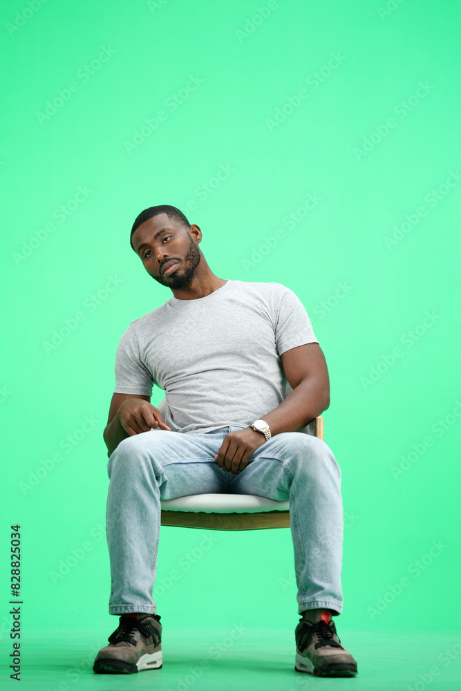 Wall mural a man, on a green background, sitting on a chair