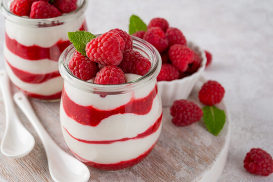 Vanilla white chocolate mousse, trifle, panna cotta or parfait with raspberry sauce in a glass jar. Sweet summer dieting dessert.