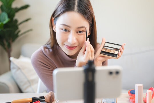 asian female beauty social media influencer livestream marketing cosmetics a make up tutorial via smartphone.