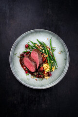 Traditionally roasted saddle of venison fillet with spätzle, vegetable and fruits in chocolate red...