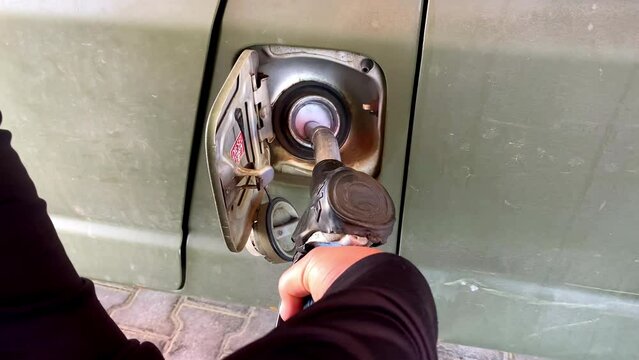 Man hand refueling filling car benzine gasoline fuel at gas station.fuel nozzle into automobile's tank, petrol prices. Filling car with gas fuel at station pump.Gasoline, petroleum