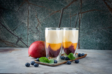 Traditional striped milk shake with mango, blueberries and buttermilk served in a glass as close-up...