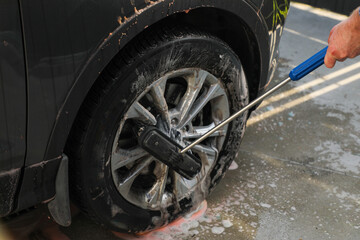 Car wheels are washed with a brush at a car wash, close-up