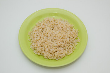 Plate of cooked brown rice on a white background