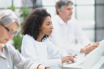 Fototapeta premium Black woman sitting at a table and using a computer