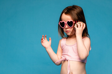 Little girl holding seashell in her hands on blue background. Girl on studio background. Child put...