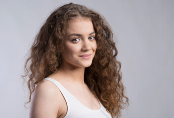 Portrait of a gorgeous teenage girl with curly hair. Studio shot, white background with copy space