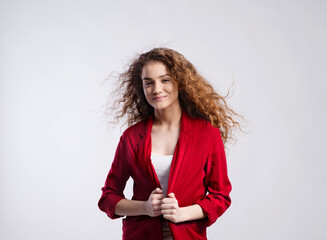 Portrait of a gorgeous teenage girl with curly hair in red blazer. Studio shot, white background...