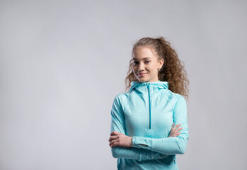 Portrait of a gorgeous fitness girl with curly hair, wearing workout clothes. Studio shot, white background with copy space