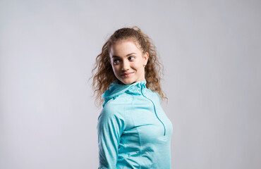 Portrait of a gorgeous fitness girl with curly hair, wearing workout clothes. Studio shot, white...