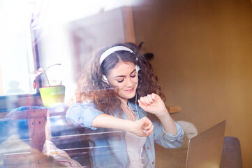 Beautiful woman with curly hair wearing headphones, listening music, positive affirmations.