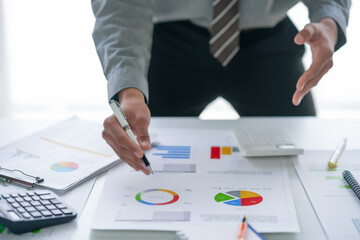 Businessman analyzing financial data and charts at office desk with pen and calculator, focusing on...