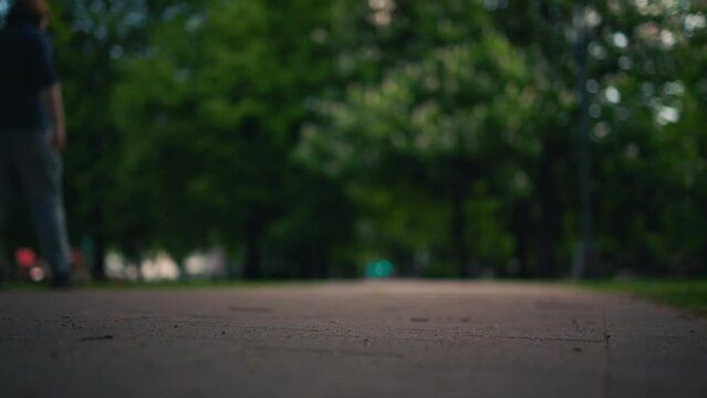 A serene view of people walking in a green park pathway with a blurred perspective
