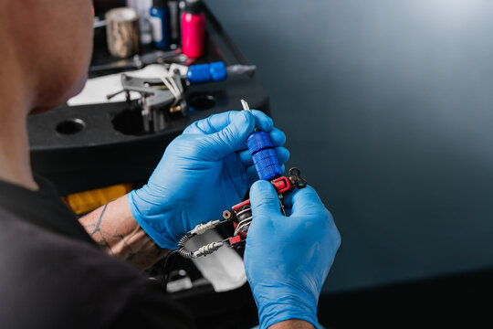 Anonymous tattoo artist preparing machine in studio