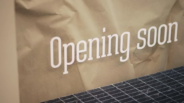 Storefront sign says Opening Soon on crumpled paper, hinting at the new business launch