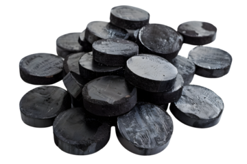 A pile of black hockey pucks, some with white streaks, lie on a PNG dicut style.