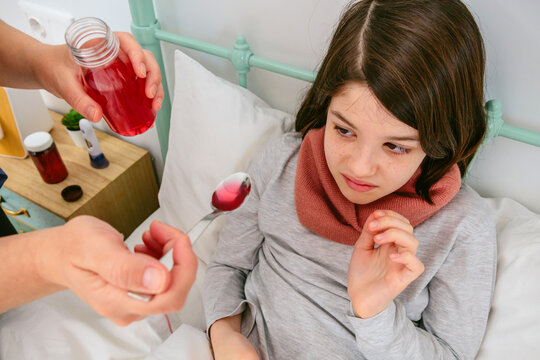 Sick Child Being Given Medicine in Bed