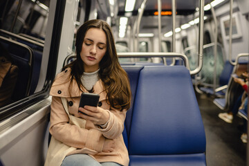 Young woman on public transport looking down at cell phone