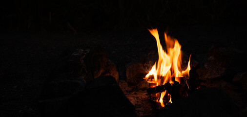 Campfire at touristic camp. Burning wood. Flame and fire sparks on dark background.