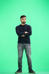 Fototapeta premium A man, full-length, on a green background, crossed his arms