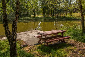 Obraz premium Park bench and table by a small pond.