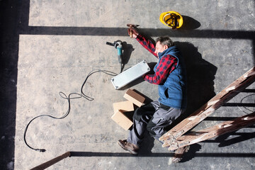 Male worker lying on the floor after fall from ladder, holding his knee. Work injury, accident in workplace.