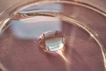 Beautiful volumetric drop of cosmetic product on a pink background.