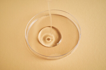 Serum or cosmetic oil flows into a transparent bowl.