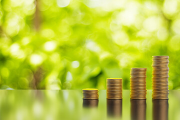 Abstract growing stacked coins on blurry green background with mock up place. Financial growth and...