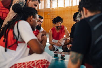 Diverse male basketball team and elderly coach discussing tactic during practice