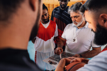Mature coach and a diverse basketball team in huddle discussing game tactic - Powered by Adobe