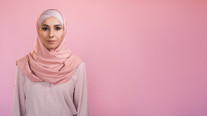 Muslim woman. Modest beauty. Portrait of confident religious girl in islamic hijab headscarf isolated on pastel pink empty space advertising background.