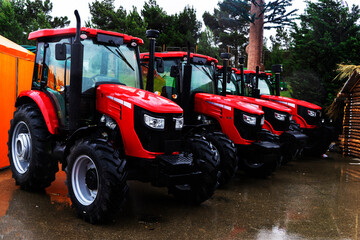 The new red agricultural tractors of various models stand in a row at the exhibition site in...