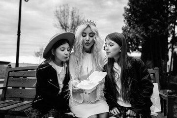 Portrait of a young beautiful mother and two daughters in a summer city.