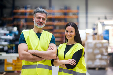 Warehouse employees in warehouse. Two workers in reflective clothing in modern industrial factory,...