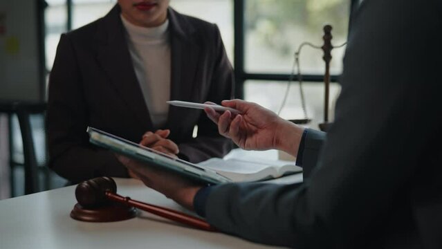 Lawyers explain and discuss matters of law and contract on tablet to clients and gavel hammer.